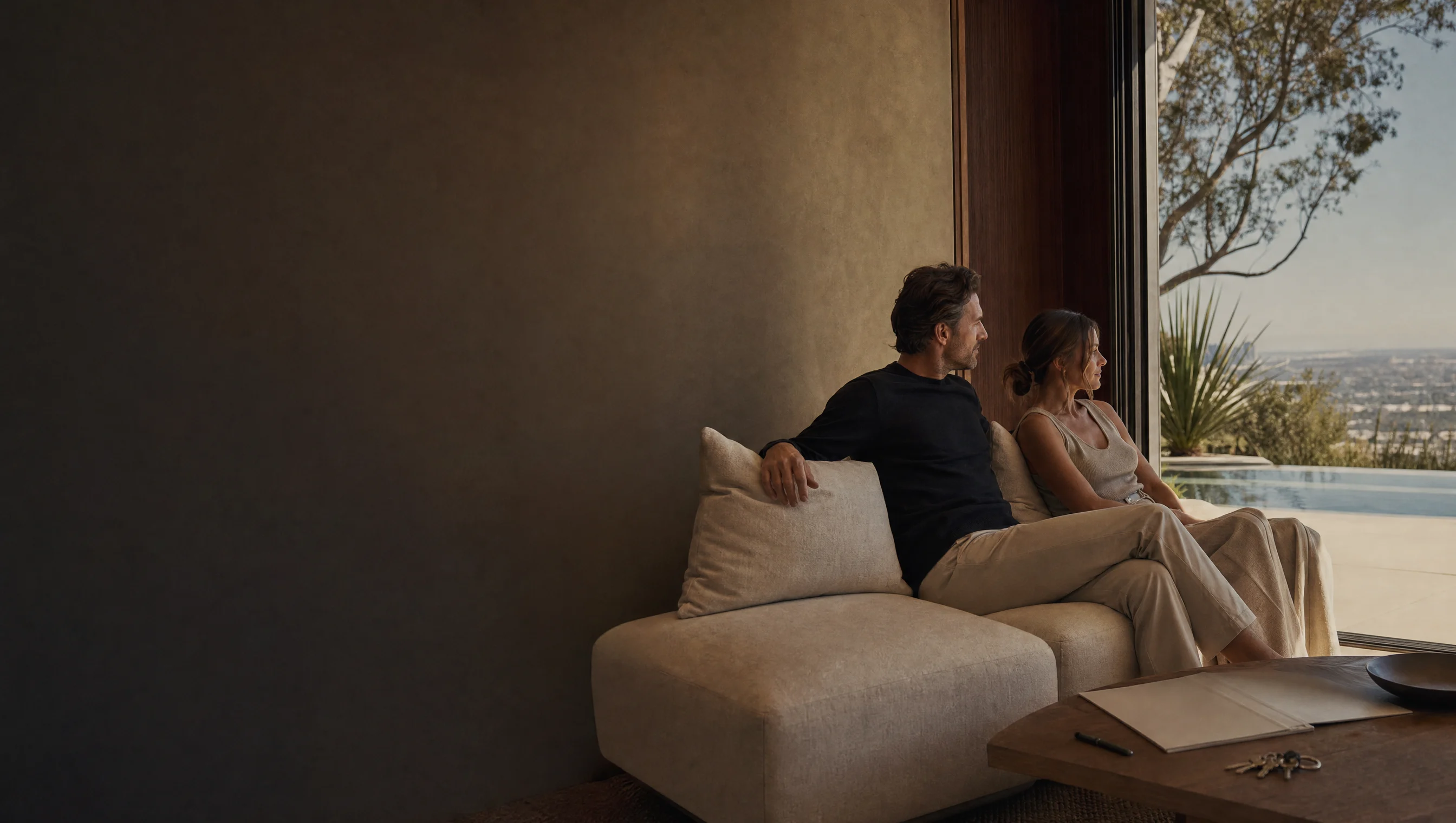 Aspirational Los Angeles living room with a couple, rental preparation folder, terrace greenery, and a horizon pool